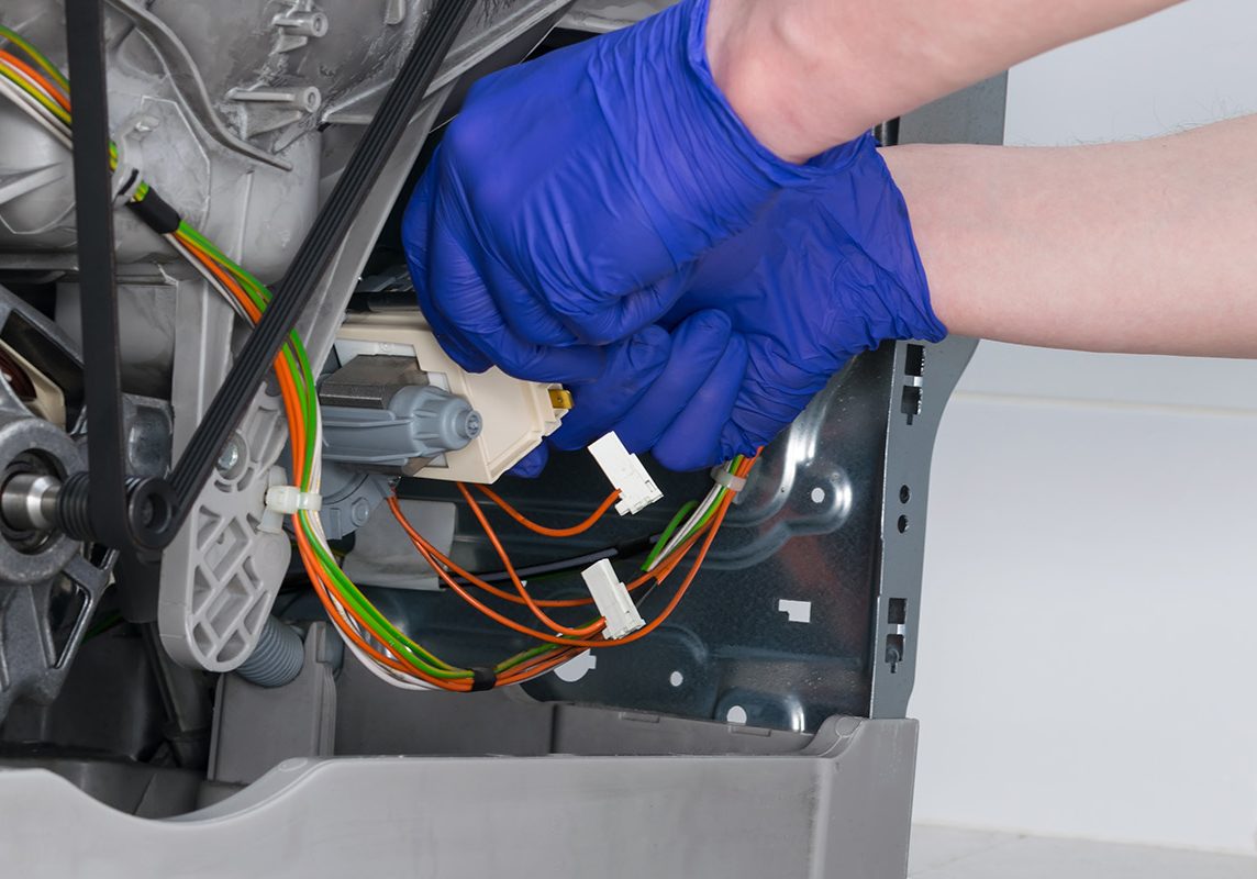 close-up of the installation of the new control unit of the washing machine mechanisms, by the master under warranty